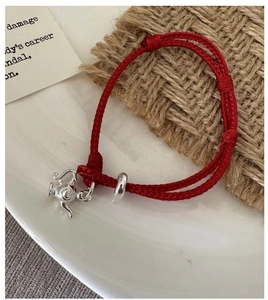 Macro shot of S925 sterling silver teapot charm on a red woven adjustable rope bracelet