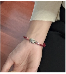 Gros plan du pendentif chat porte-bonheur en argent S925 sur bracelet tressé rouge