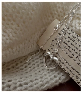 Detailed close-up of S925 sterling silver hollow heart pendant on knitted sweater