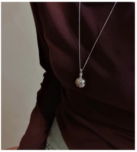 Close-up of minimalist S925 sterling silver long necklace with round pendant on model