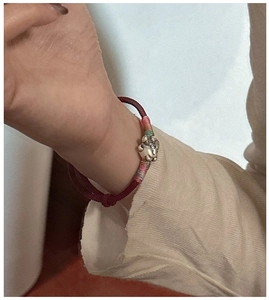 Gros plan du bracelet chat porte-bonheur en argent S925 et corde tressée rouge au poignet