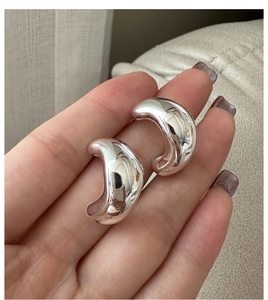 Close-up of polished S925 sterling silver C-shaped hoop earrings with a glossy finish
