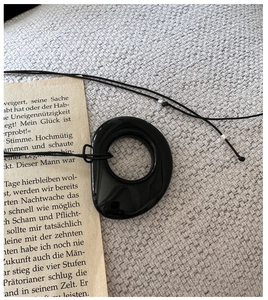 Close-up of a minimalist black obsidian irregular pendant necklace on vintage book pages