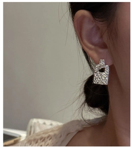 Close-up of S925 silver rectangular drop earrings with textured hammered metal finish