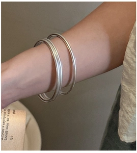 Detailed view of three minimalist matte silver stackable bangles on a wrist