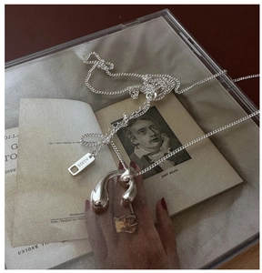 Detail showing irregular fluid silver pendant and AG925 hallmark on minimalist chain