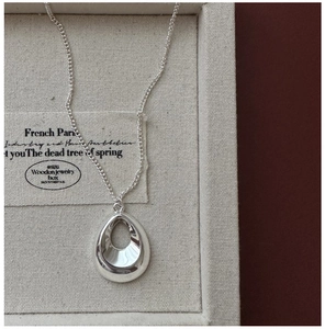 Vue macro du pendentif goutte en argent et chaîne fine dans son écrin à bijoux