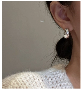 Macro detail of chunky S925 sterling silver C-shape hoop earrings on a model ear