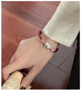Gros plan du pendentif chat porte-bonheur en argent S925 sur bracelet rouge tressé