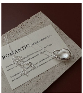 Gros plan d'un pendentif en argent en forme de goutte d'eau avec un design fluide