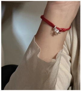 Close-up of S925 silver teapot charm on red braided rope bracelet worn on a wrist