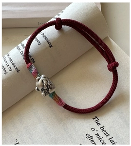 Vue macro de la breloque chat porte-bonheur en argent S925 sur bracelet rouge tressé