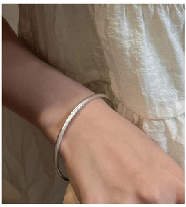 Detailed view of a minimalist S925 sterling silver frosted bangle on a model's wrist