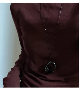 Detailed view of an irregular black obsidian ring pendant on a long cord over a knit sweater