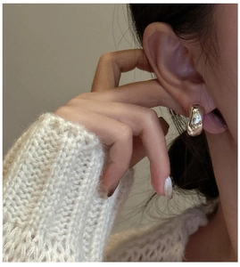 Detail of silver S925 C-shaped earring featuring a sleek mirror finish on a female model