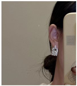 Detailed view of S925 sterling silver drop earrings with hammered texture on ear