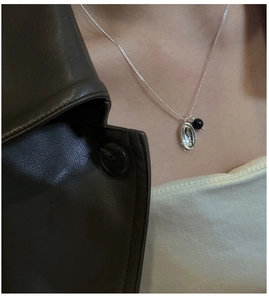 Detail of S925 silver necklace featuring a silver oval pendant and black agate bead