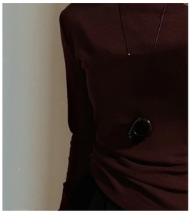 Detail of a vintage obsidian pendant necklace paired with a dark red knitted sweater