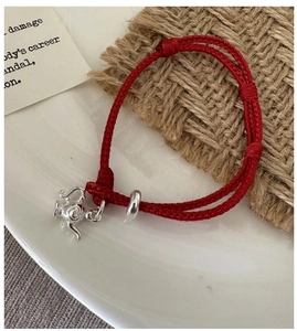 Close-up of S925 sterling silver teapot charm on a braided red rope bracelet