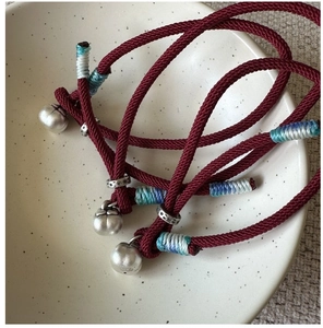 Detail of S925 sterling silver persimmon charm and red cord with blue silk wrap
