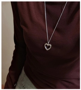 S925 sterling silver hollow heart pendant necklace worn on a dark red sweater