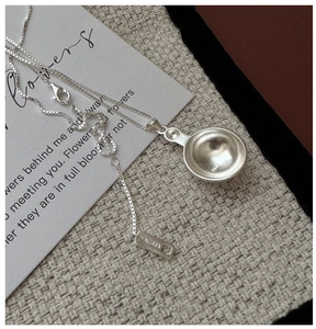 Macro shot of S925 sterling silver necklace featuring an AG925 hallmark tag and hemisphere pendant