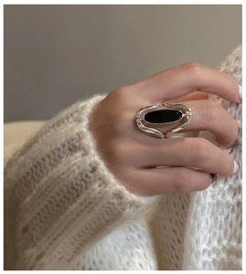 Detail of silver S925 ring with oval black agate worn with white knitted sweater