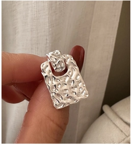 Macro view of silver earrings with hammered texture and irregular rectangular design