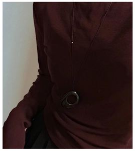 Artistic detail of S925 silver obsidian long pendant necklace on a red sweater