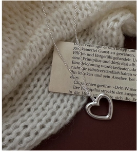 Detail of S925 sterling silver hollow heart pendant on textured knit fabric