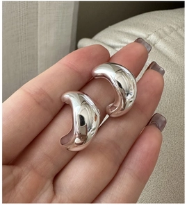 Close-up of minimalist S925 silver C-shape hoop earrings with a polished glossy finish