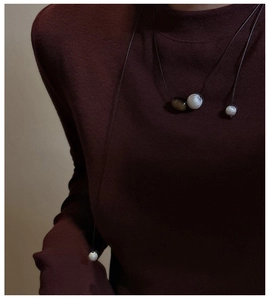 Close-up of minimalist S925 silver brushed bead necklace worn on a burgundy sweater