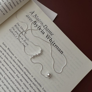 Elegant 925 sterling silver Y-shaped snake chain necklace with sliding beads on a book