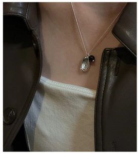 Detail of S925 sterling silver necklace featuring a silver bean and black bead pendant