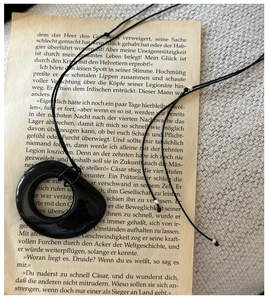Detail shot of irregular black obsidian pendant on vintage book with silver beads