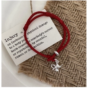 Close-up of S925 silver teapot charm on adjustable red braided rope bracelet