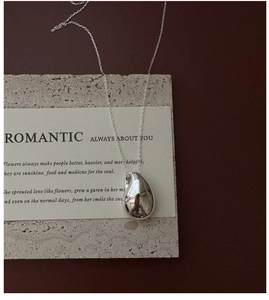 Détail macro du pendentif goutte en argent sur chaîne fine sur pierre texturée