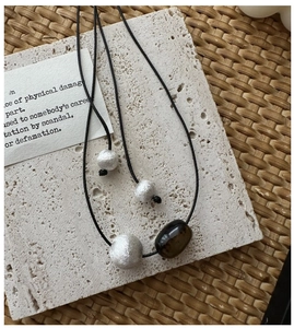 Detail of a handmade long necklace with brushed silver beads on textured stone