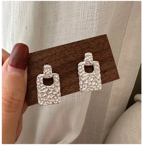 Close-up of S925 sterling silver rectangular earrings with hammered lava texture