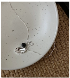 Macro shot of S925 silver necklace featuring black agate bead and silver oval metal pendant