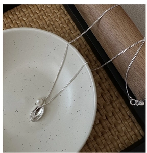 Detail of S925 silver necklace with polished oval pendant and glossy white pearl