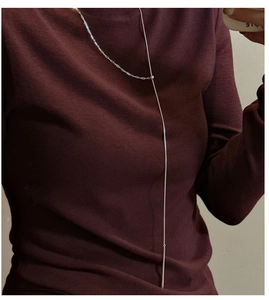 Detail of S925 silver Y-shaped lariat necklace with long drop tassel on maroon sweater