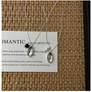 Close-up of S925 sterling silver necklaces with black bead and white pearl on oval pendants