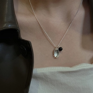 S925 silver necklace with textured oval pendant and black bead worn on collarbone