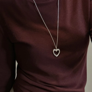 Elegant S925 sterling silver hollow heart pendant necklace worn on deep red sweater