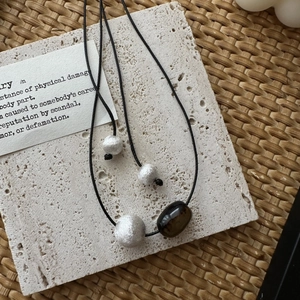 Minimalist S925 silver necklace with brushed beads and brown stone on travertine stone