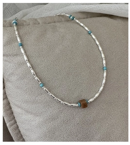 Detail of S925 silver rice beads and turquoise stones with a brown cube pendant