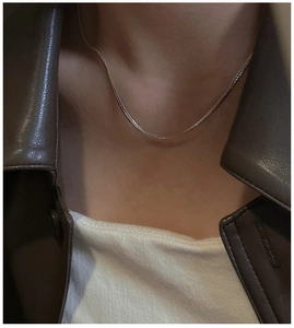 Close-up of minimalist S925 sterling silver flat snake chain worn with a leather jacket
