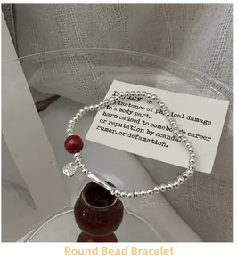 Detailed shot of silver bead bracelet with red cinnabar bead and Fu character charm