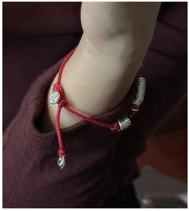 Close-up of red braided rope bracelet with S925 sterling silver beads on a wrist
